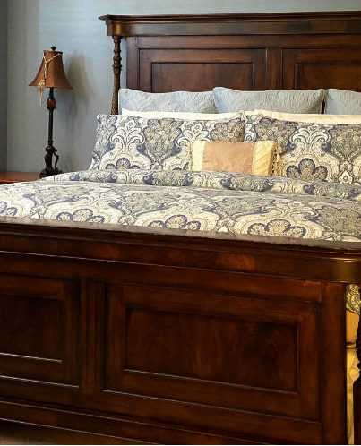 Large Oak King bed with Paisley comforter and lamp on bedside table
