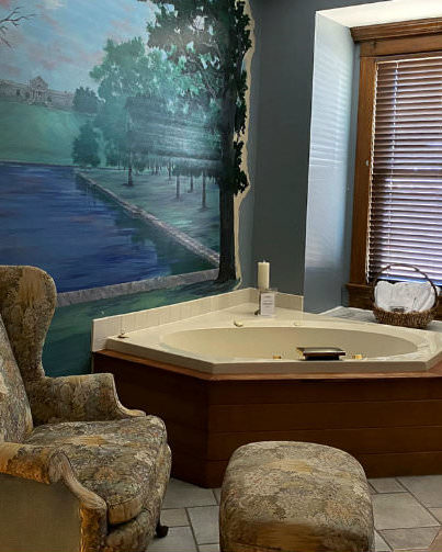 Two person jetted tub in sitting area with Forest Park mural on the wall