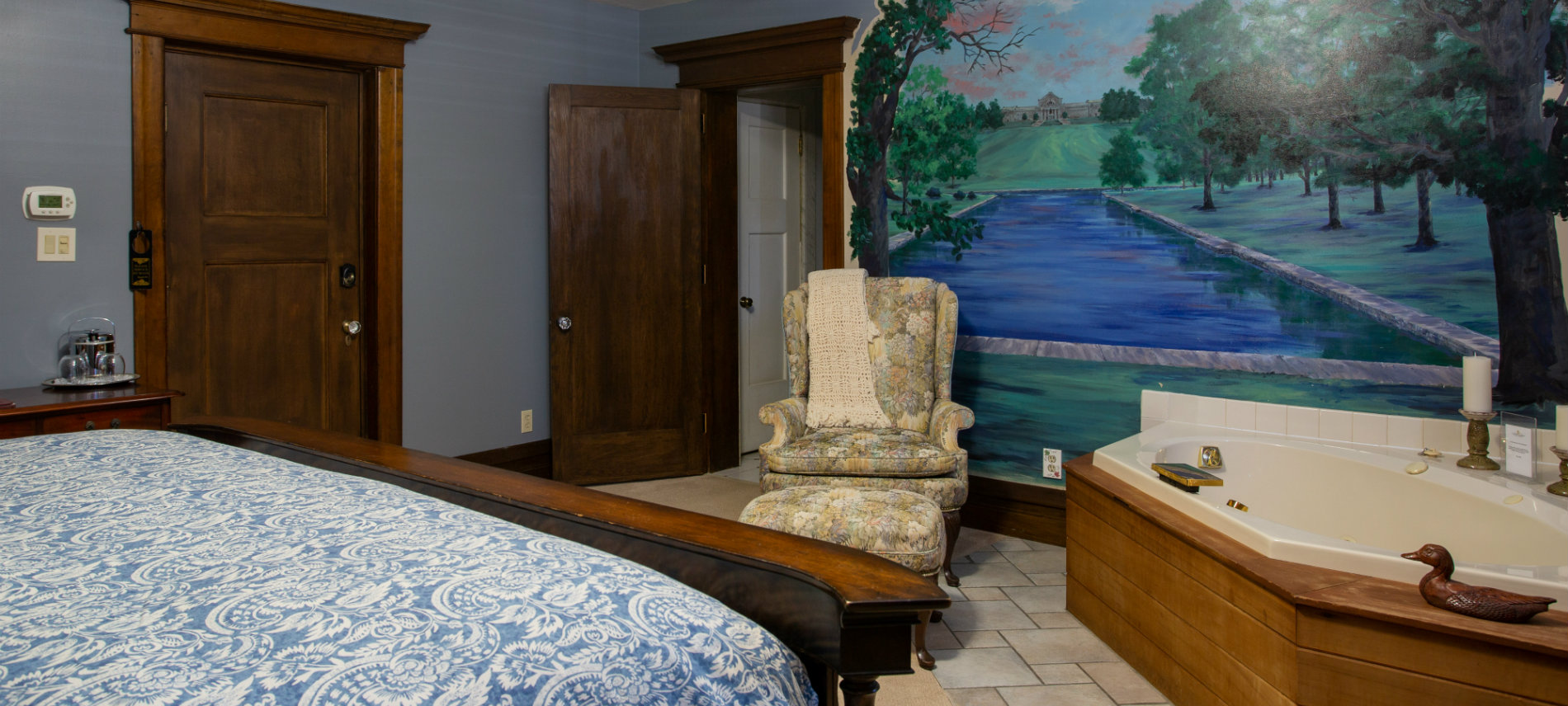 Large Oak bed with paisley comforter, two person jetted tub in front of painted mural